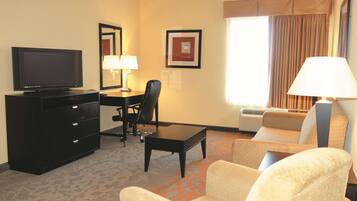 Een hotelkamer met een flatscreen-tv, een bureau met stoel, een bank en een lamp.