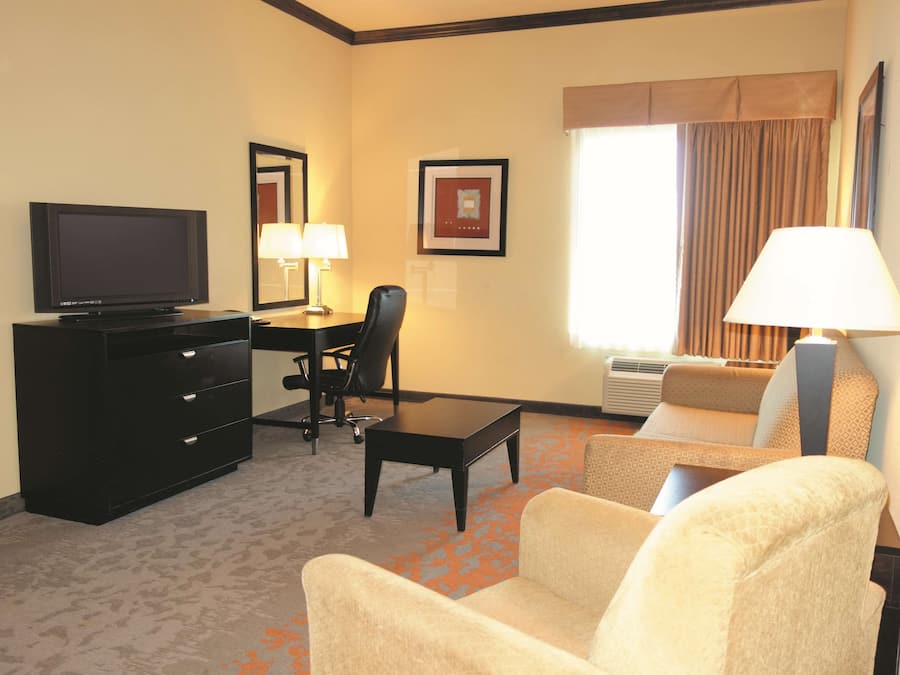 Een hotelkamer met een flatscreen-tv, een bureau met stoel, een bank en een lamp.