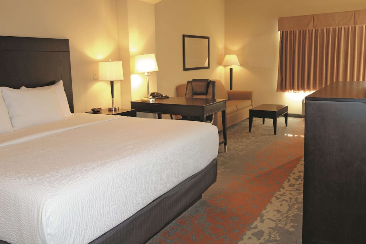 Una habitación de hotel con una cama grande, un escritorio, una silla y una mesita.