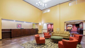 A lobby with a reception desk, seating area with armchairs, a patterned rug, and a bar area. - La Quinta Inn & Suites by Wyndham Eastland (Eastland)