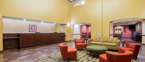 A lobby with a reception desk, seating area with armchairs, a patterned rug, and a bar area.