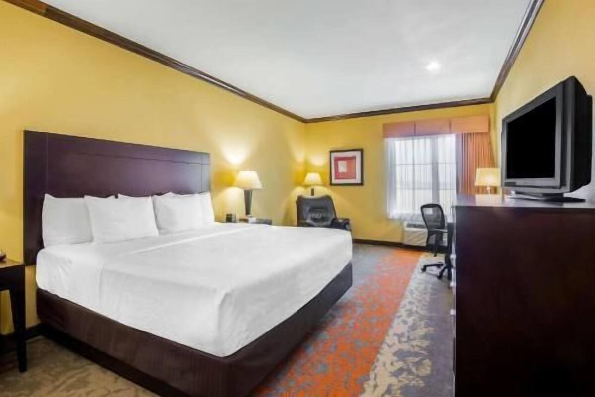 Una habitación de hotel con una cama grande, un escritorio con televisor y una silla.