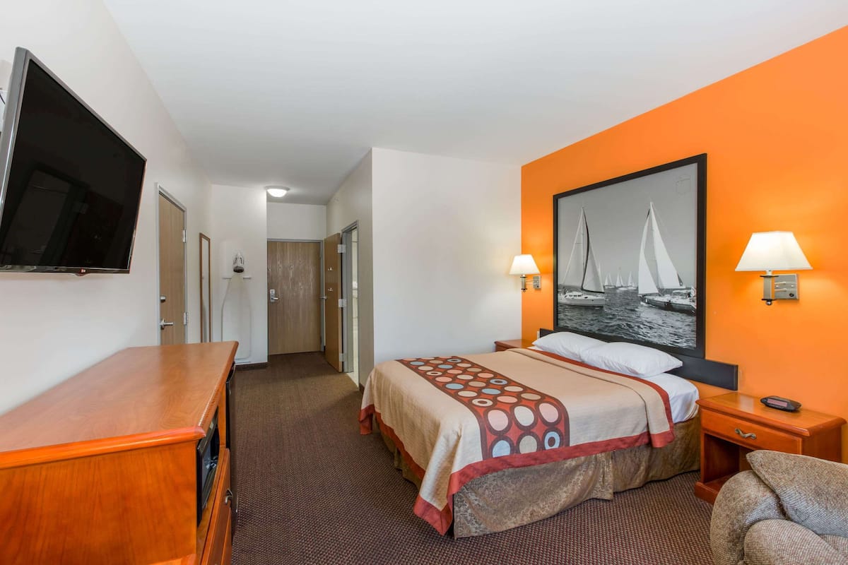 Una habitación de hotel con cama, televisión, escritorio y silla.