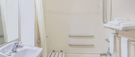 A modern bathroom with a sink, mirror, shower, and towel rack.