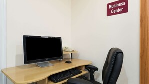 Een bureau voor een business center met een computer, toetsenbord en stoel.