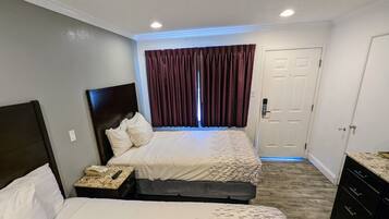 A hotel room with two beds, a desk with a telephone, a door, and a window with curtains.