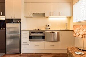 Una cocina moderna con electrodomésticos de acero inoxidable, armarios blancos y piso de madera.