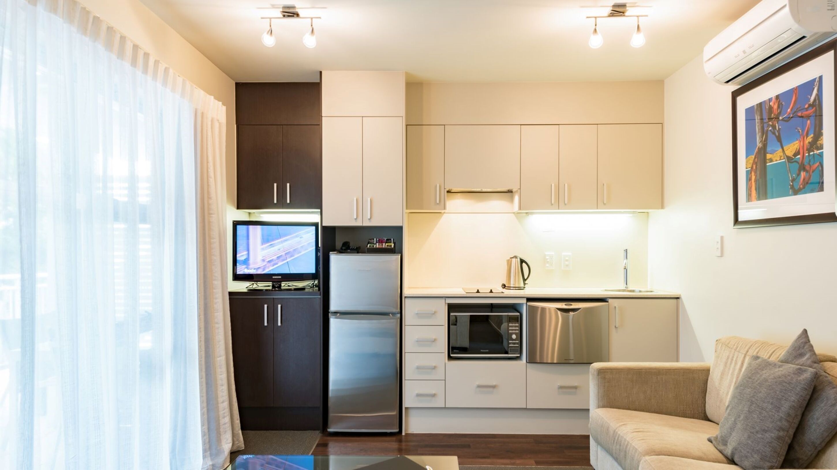 A compact kitchen with a refrigerator, microwave, and stove, a small dining area, and a sofa.