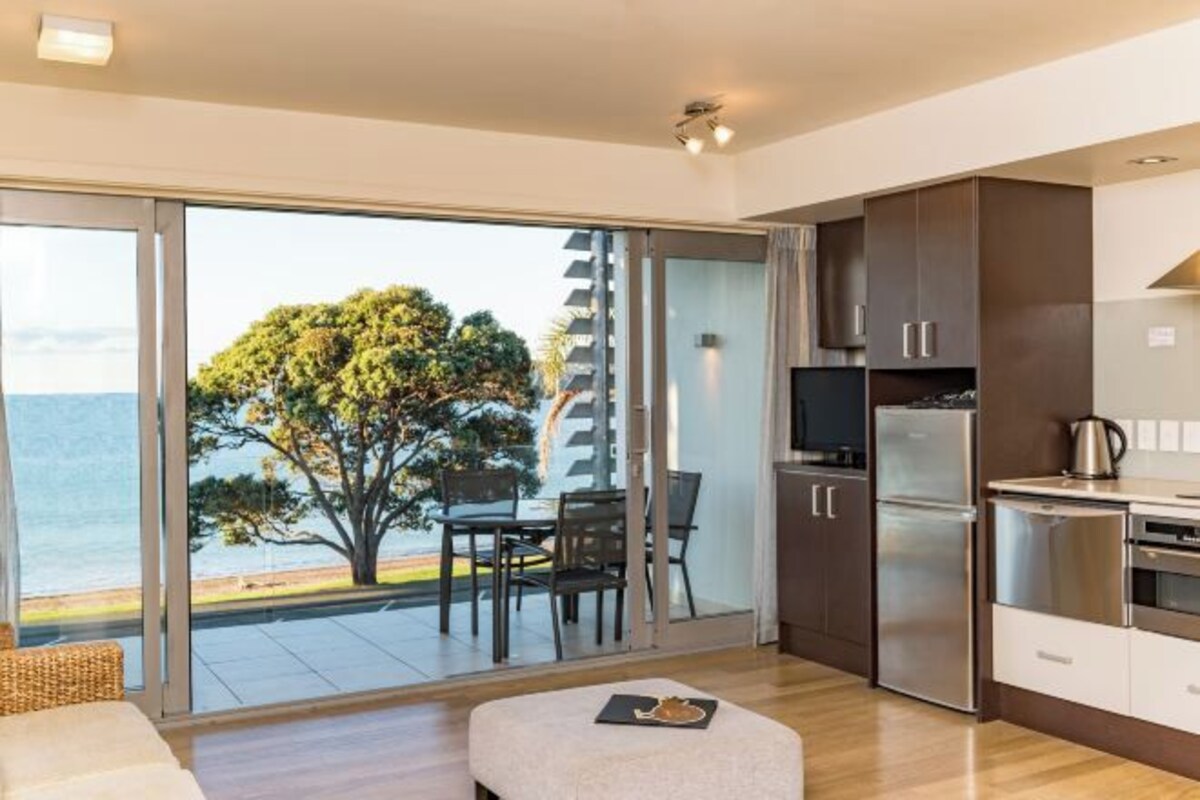 A modern kitchen with a large window, sliding glass door, and a dining area with a table and chairs.