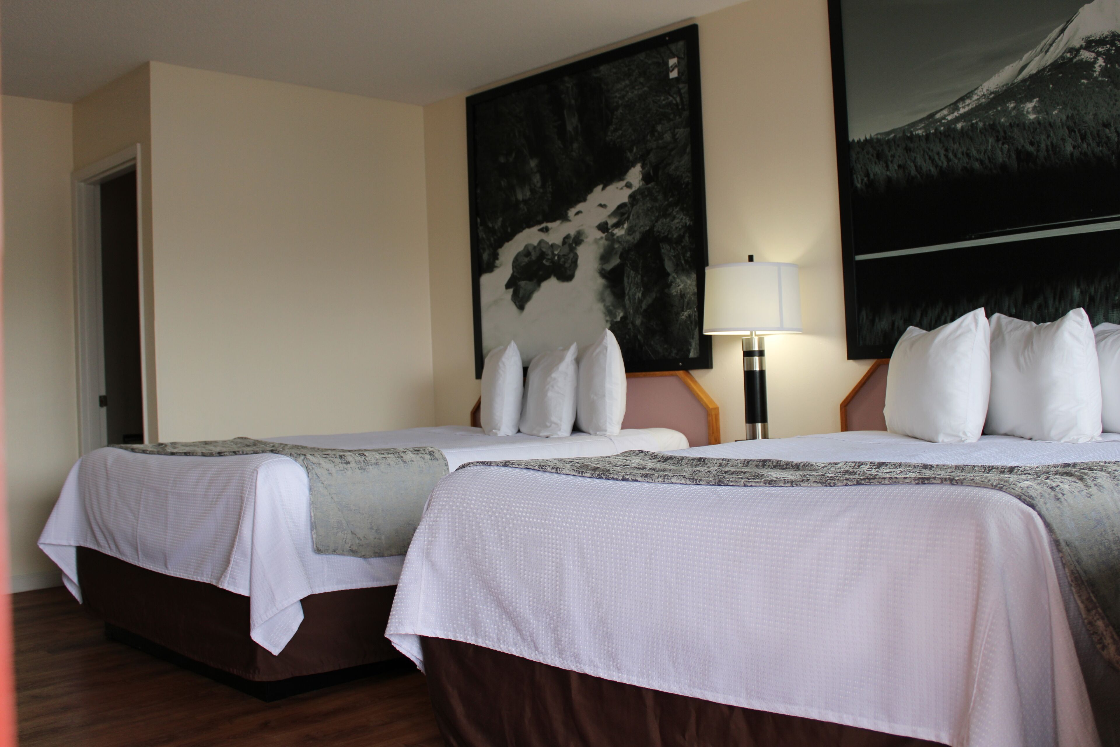 Une chambre d’hôtel avec deux lits, un grand tableau au mur et une lampe.