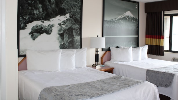 A hotel room with two beds, a large framed picture of a mountain, a lamp, and a window with curtains. - Baymont by Wyndham (Ashland)