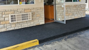 A building with a stone facade, a glass door entrance, and a visible interior with a counter and signage. - Baymont by Wyndham (Ashland)