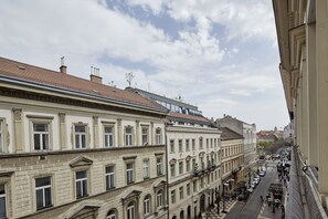 A street view of a historic building with classical architecture, a covered pedestrian walkway, and a clear sky. - Hotel Central Basilica (Budapest)