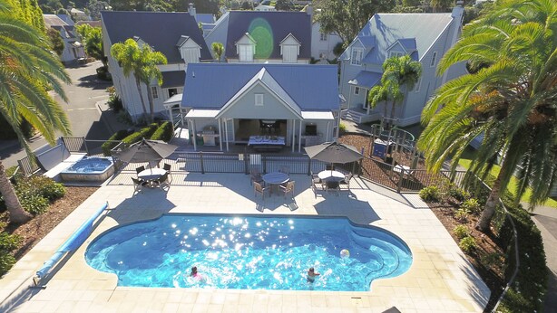 A swimming pool with lounge chairs, a hot tub, and a covered patio area. - Russell Cottages Tanoa Hotels (Russell)