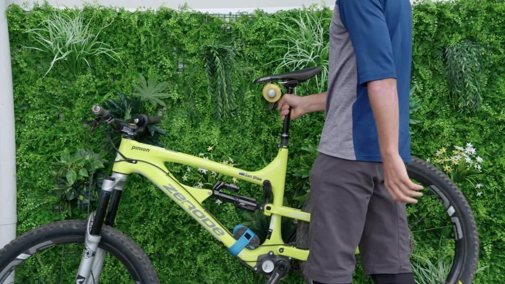 Een persoon staat naast een gele fiets, met 'pinion' en 'zerode' op de frame zichtbaar.