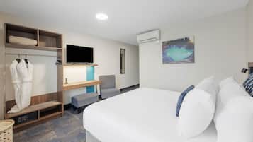 Una habitación de hotel moderna con una cama grande, zona de estar, armario, televisor de pantalla plana y aire acondicionado.