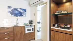 A modern kitchen with a microwave, coffee maker, and a shelf with cups and a kettle. - JetPark Hotel Rotorua (Rotorua)