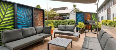 Un espacio al aire libre con patio, sofá, sillón y mesa.