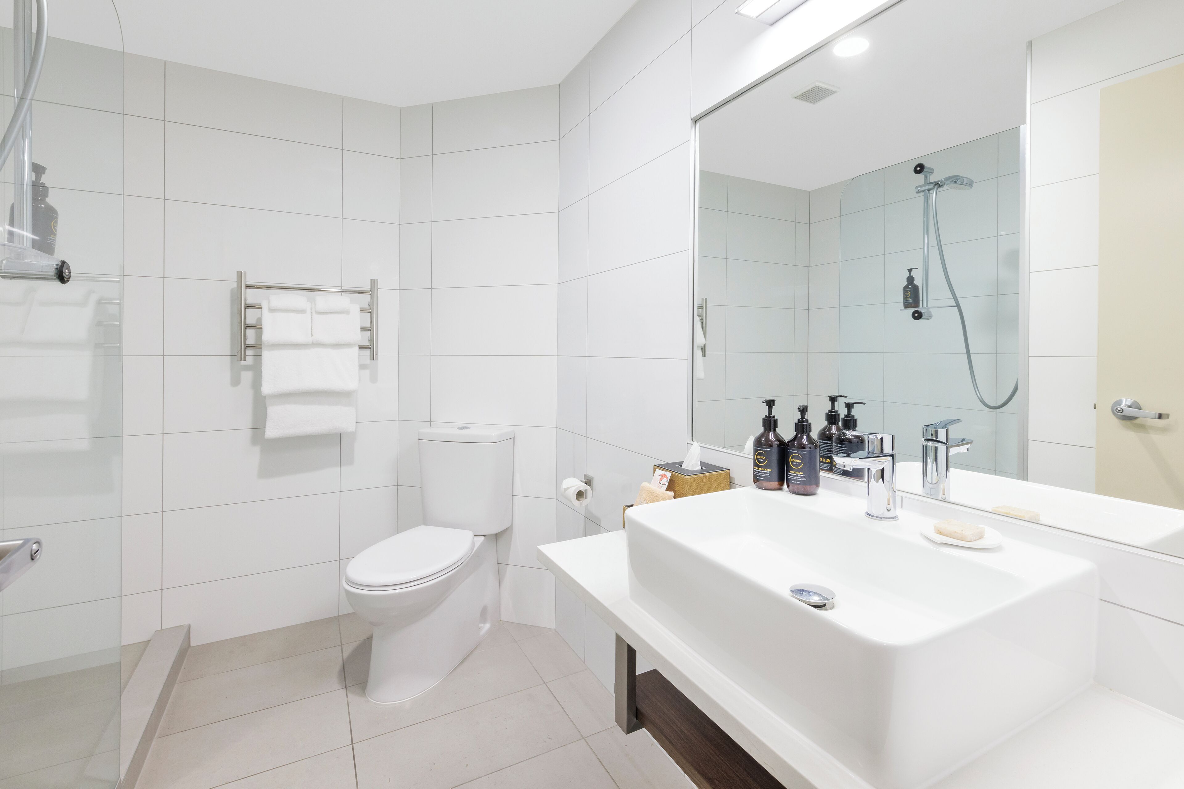 A modern bathroom with a white sink, mirror, and toilet.