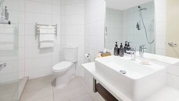 A modern bathroom with a white sink, mirror, and toilet.