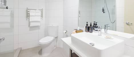 Un baño moderno con lavamanos, espejo y retrete blancos.