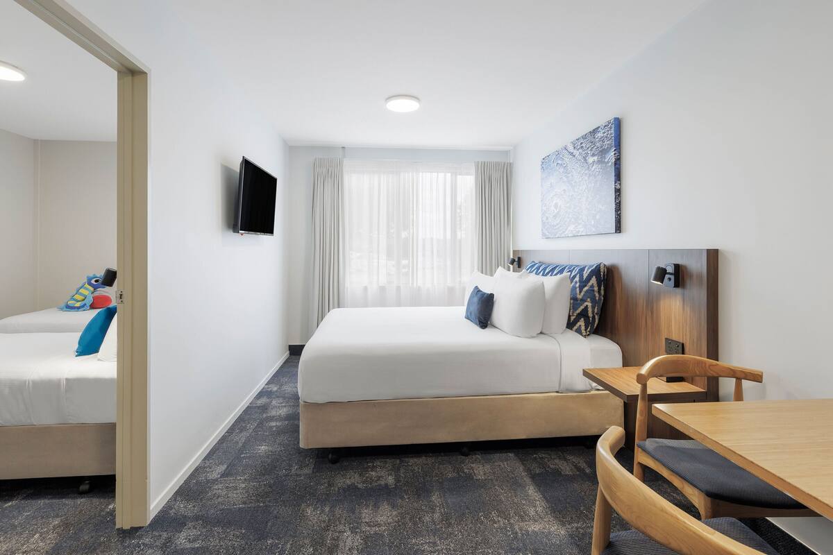 A hotel room with a bed, a desk, and a TV.