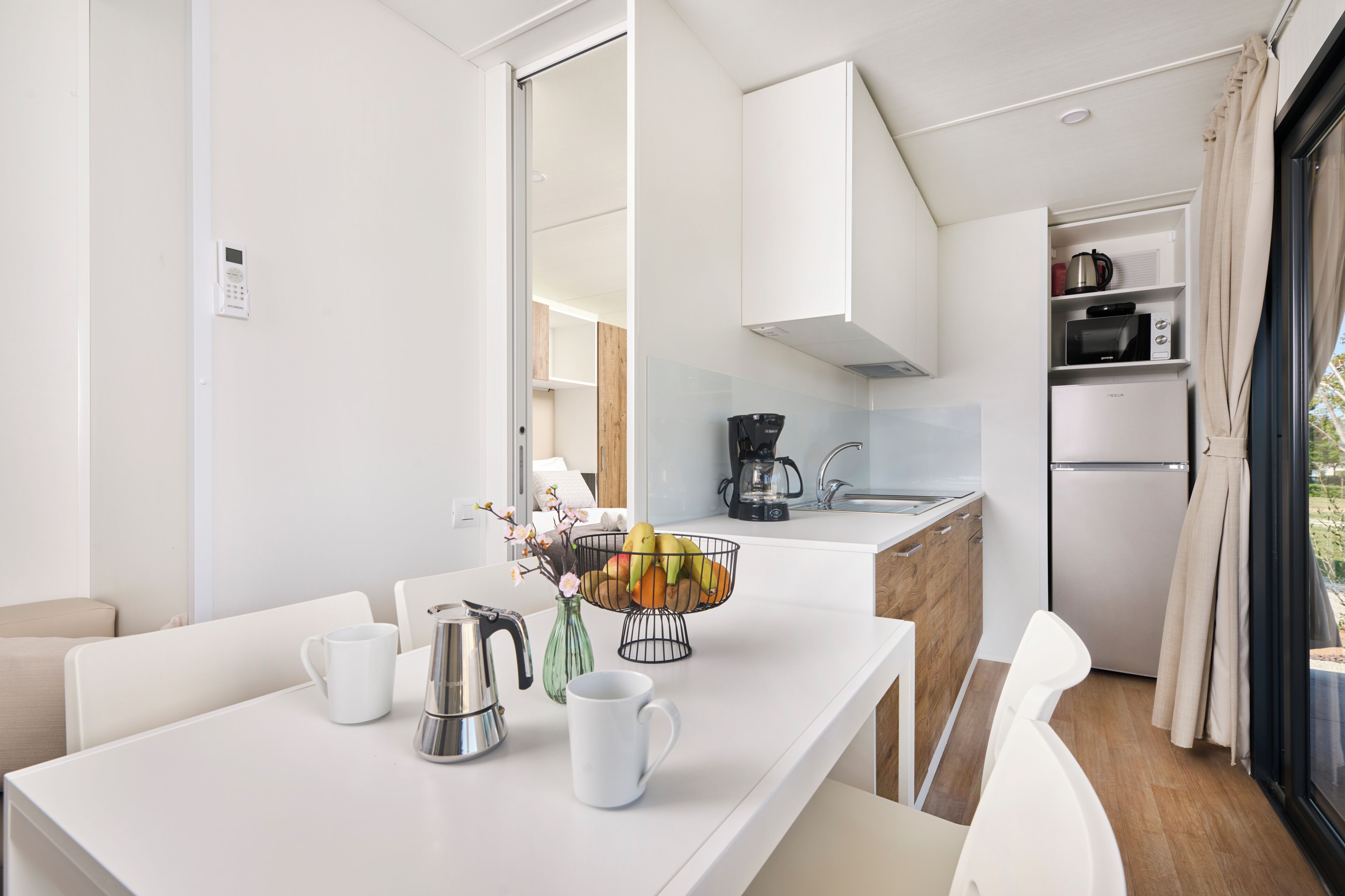 A modern kitchen with a coffee maker, a fruit bowl, and a kettle on the counter.