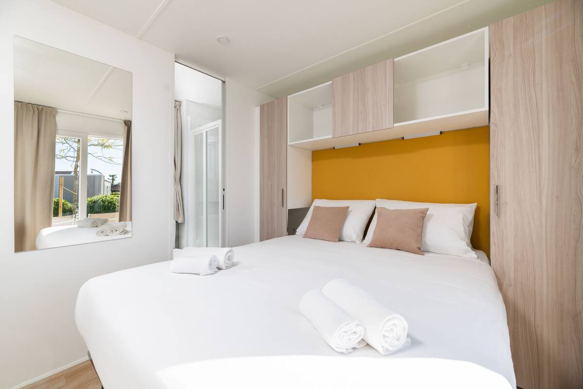 Una habitación de hotel moderna con una cama grande, un armario empotrado y una ventana con cortinas.