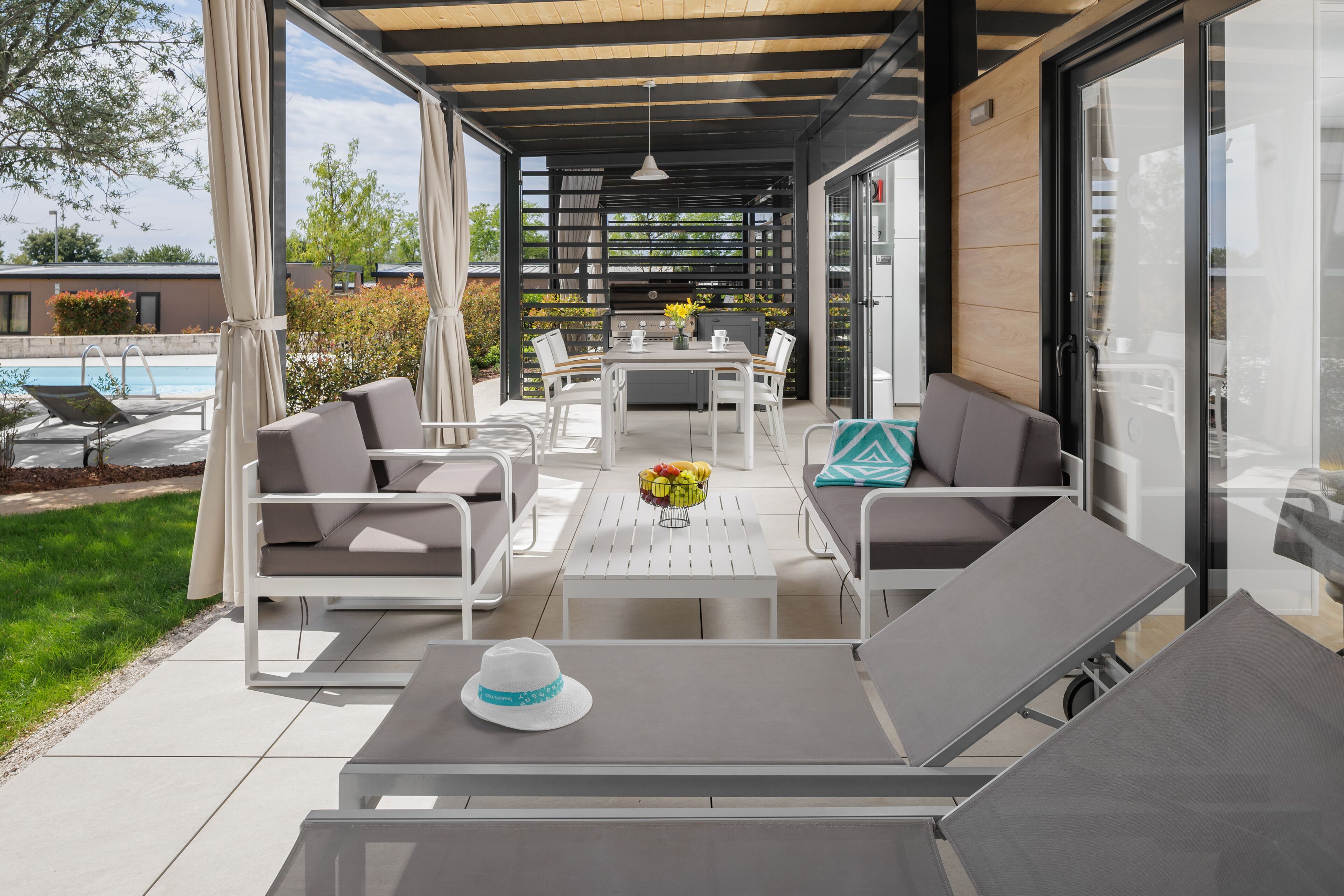 An outdoor patio area with a table, chairs, and a grill.