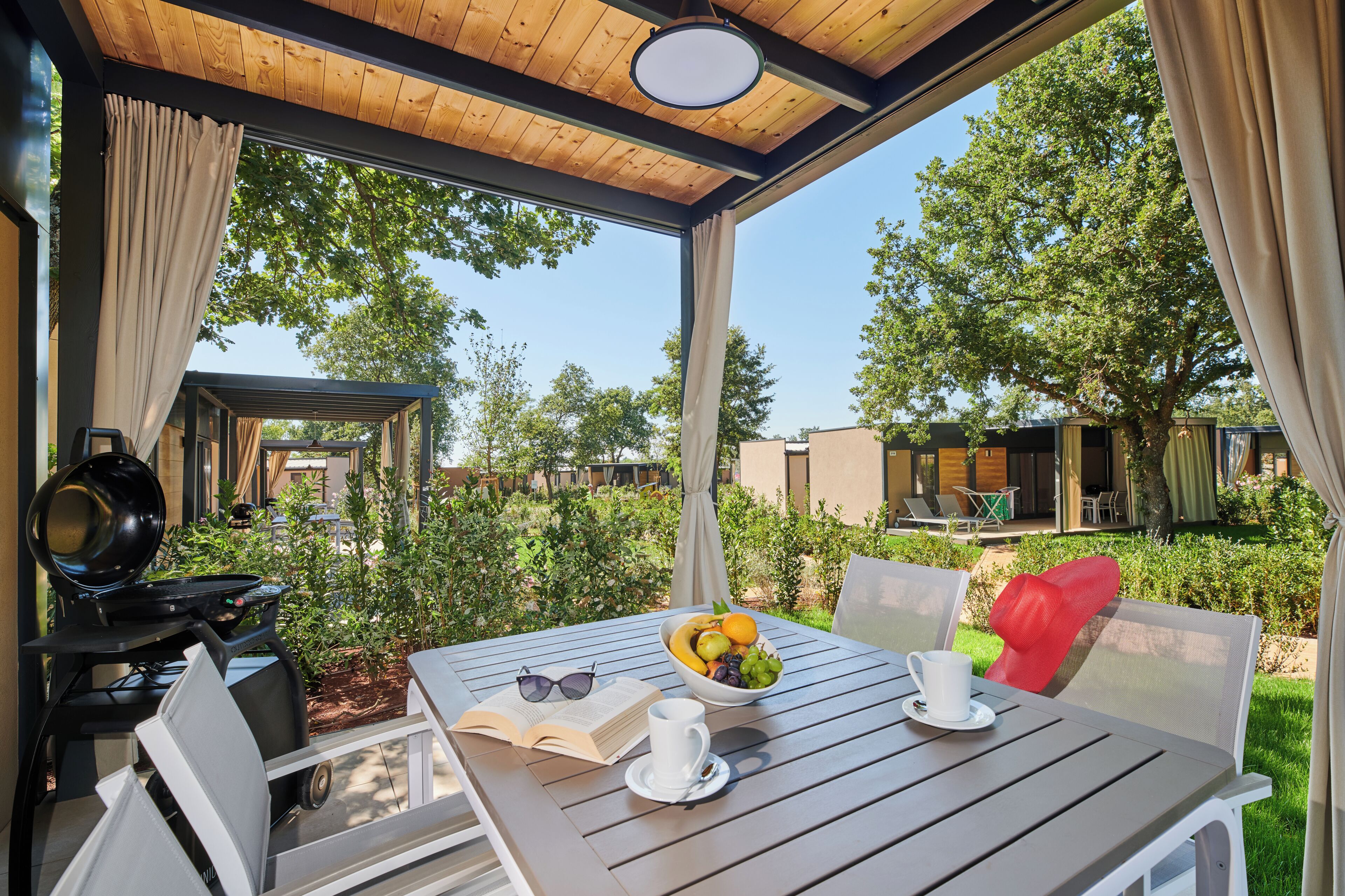 An outdoor patio with a table set for two, a grill, and a view of the surrounding area.