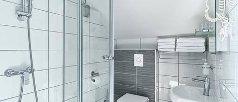 A modern bathroom with a glass-enclosed shower, a toilet, and a sink.