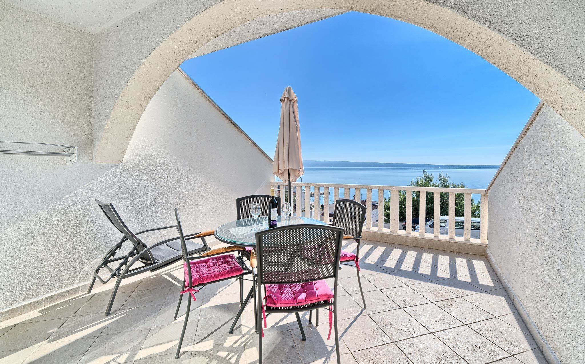 Un balcone con tavolo e sedie, vista su una distesa d'acqua.
