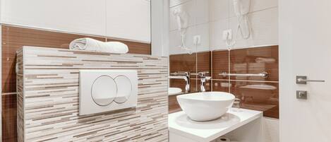A modern bathroom with a large mirror, a white sink, and a towel rack.