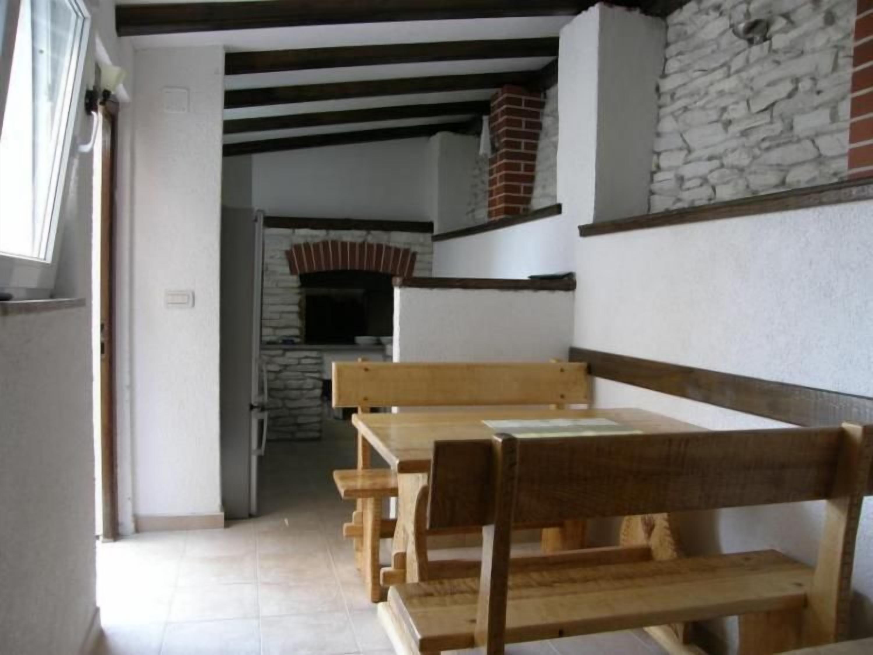 Un couloir étroit, avec un banc en bois et une table, qui mène à une cheminée en pierre.