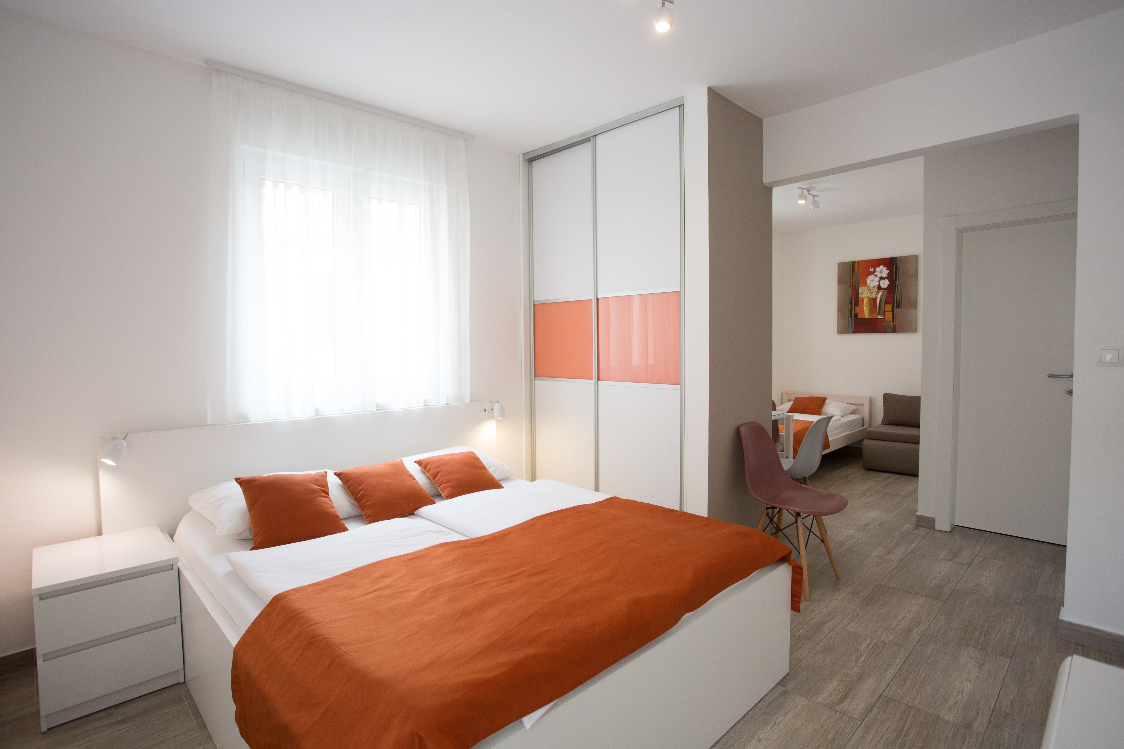 Un dormitorio moderno con una cama grande, una mesita de noche, un escritorio y una silla.