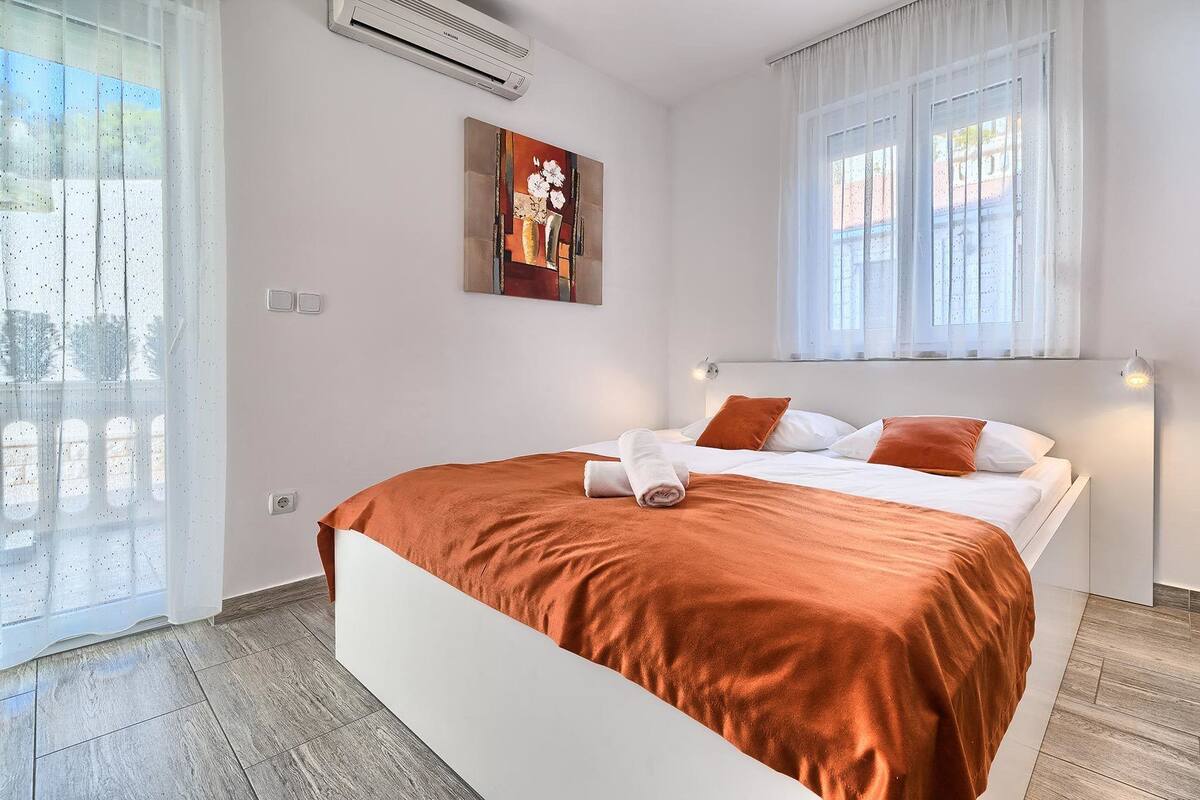 A modern bedroom with a bed, a painting, and a window.