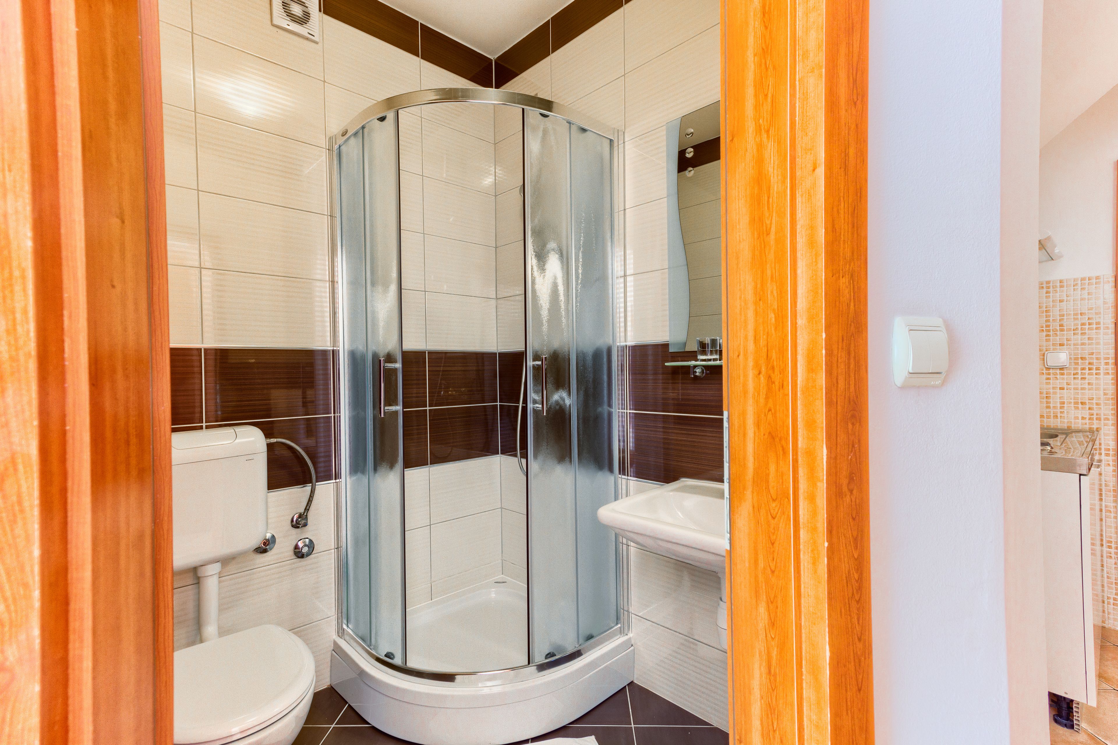 Un bany amb dutxa tancada amb vidre, un vàter i un lavabo.