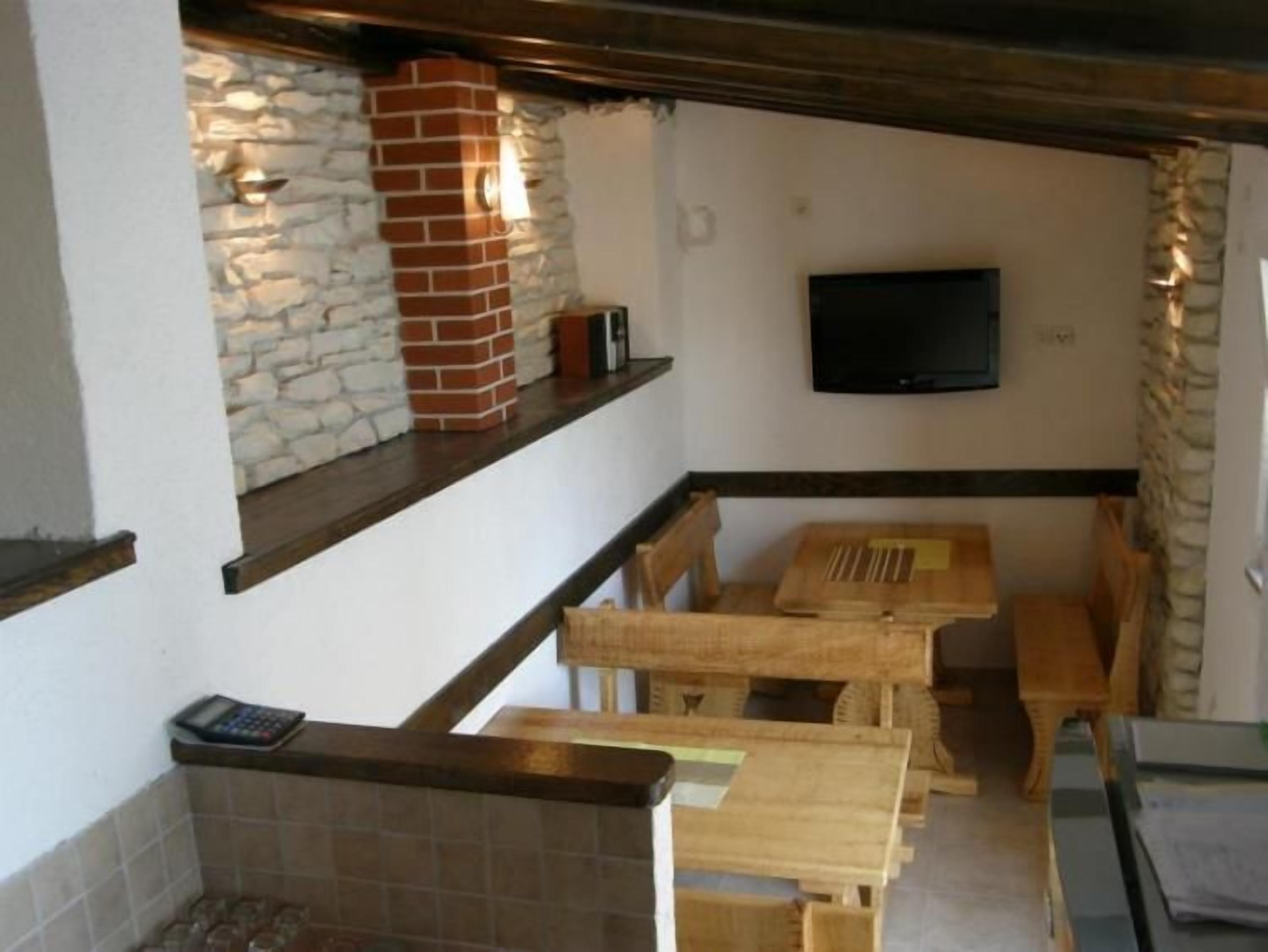 Una cocina con pared de piedra, chimenea de ladrillo, televisor montado en la pared y muebles de madera.