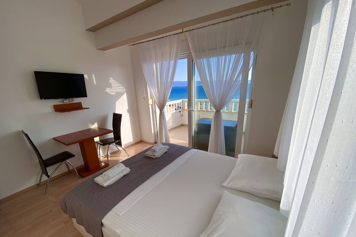 A hotel room with a bed, a TV, a desk, and a chair.