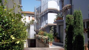 A courtyard with a stone pathway, potted plants, and a staircase leading to an upper level. - Empoli Hotel (Empoli)