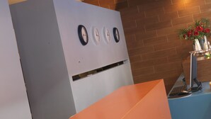 A reception area with a modern design, featuring a reception desk, a wall-mounted clock, and a small plant arrangement. - Empoli Hotel (Empoli)