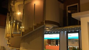 A hotel lobby with a reception desk, a staircase, and a glass railing. - Empoli Hotel (Empoli)
