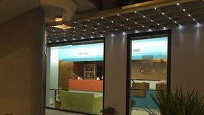A hotel lobby with a reception desk, a bar area, and a seating area with potted plants. - Empoli Hotel (Empoli)