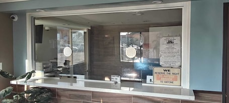 A reception area with a glass partition, a sign indicating service reservation rights, and a visible door.. Del Playa Inn Oxnard Near Camarillo
