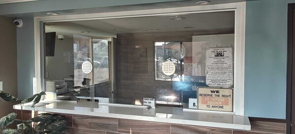 A reception area with a glass partition, a sign indicating service reservation rights, and a visible door.