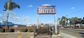 A motel sign with 'Del Playa Inn' and 'MOTEL' text, surrounded by a fenced area with palm trees and a clear sky. - Del Playa Inn Oxnard Near Camarillo (Oxnard)