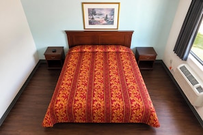 A hotel room with a large bed, two bedside tables, a framed picture on the wall, and a window with curtains.