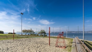 Una cancha de voleibol de playa con una red, un banco de madera y un puesto de salvavidas.