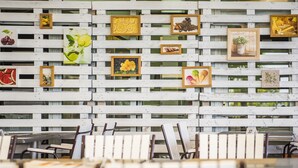 Un comedor con mesas y sillas de madera blanca, y una pared decorada con varias fotos enmarcadas.