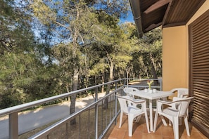 A balcony with white plastic chairs and a table, overlooking a road and trees. - Apartments Kanegra Plava Laguna (Buje)